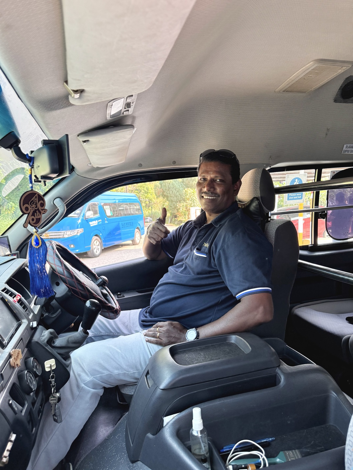 Tan Bus driver in uniform inside a company vehicle