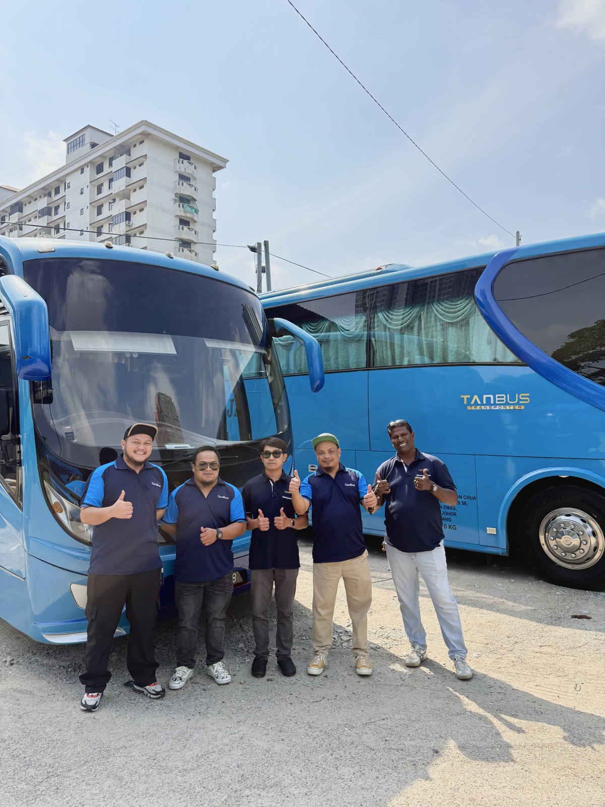 Tan Bus drivers in uniform standing beside company buses